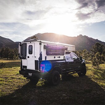 卡车露营车，车顶系统使用 LINAK LA36 电动推杆，停放在草地上。