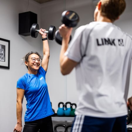 LINAK（力纳克）员工在 LINAK（力纳克）健身房中锻炼，举起哑铃。
