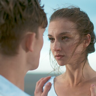 两名穿着白色衣服的年轻人专注地看着彼此。