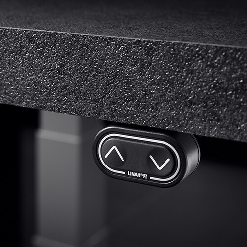 安装在桌面下方的 LINAK DPF 控制器的特写图，背景中有一个升降柱。