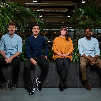 LINAK（力纳克）的四名员工坐在生产区域前。