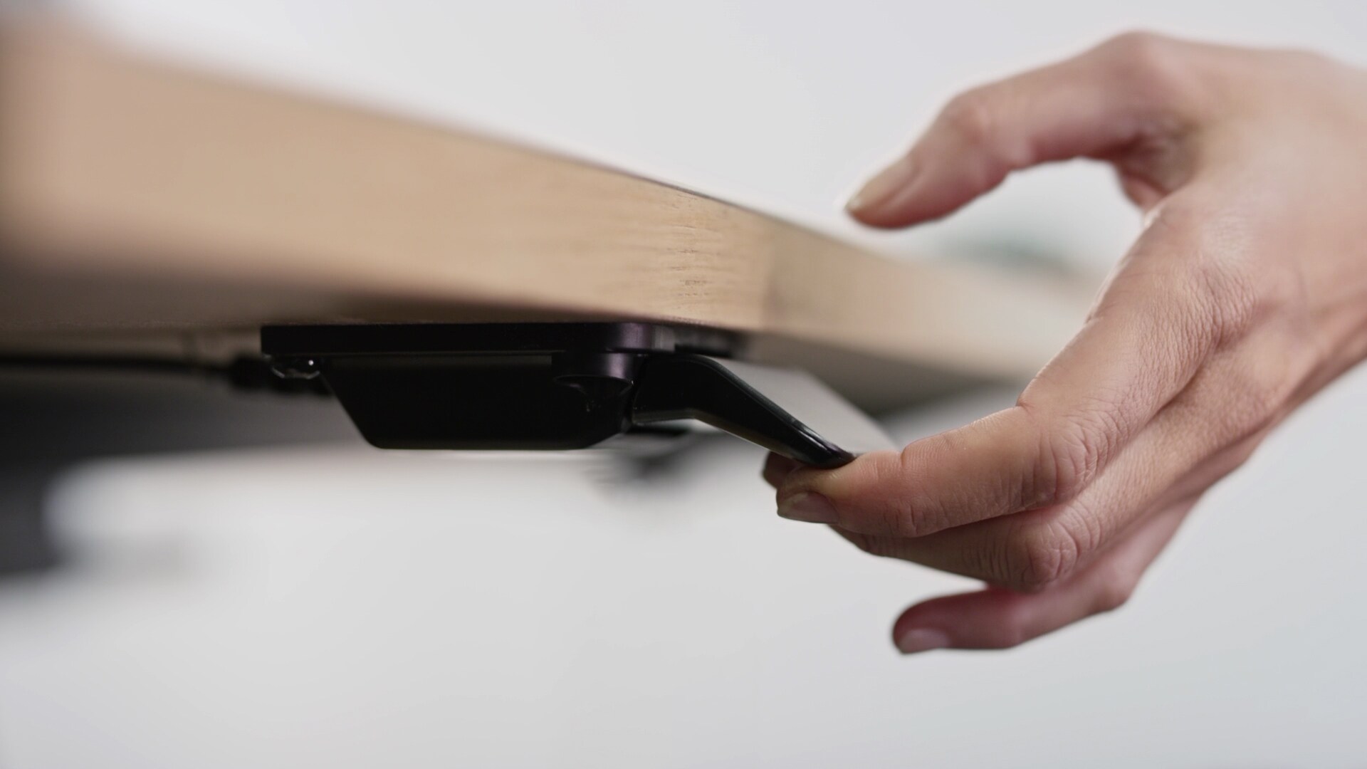 用手略微倾斜 LINAK DPI 桌面板，可调整现代办公环境的电动升降桌。