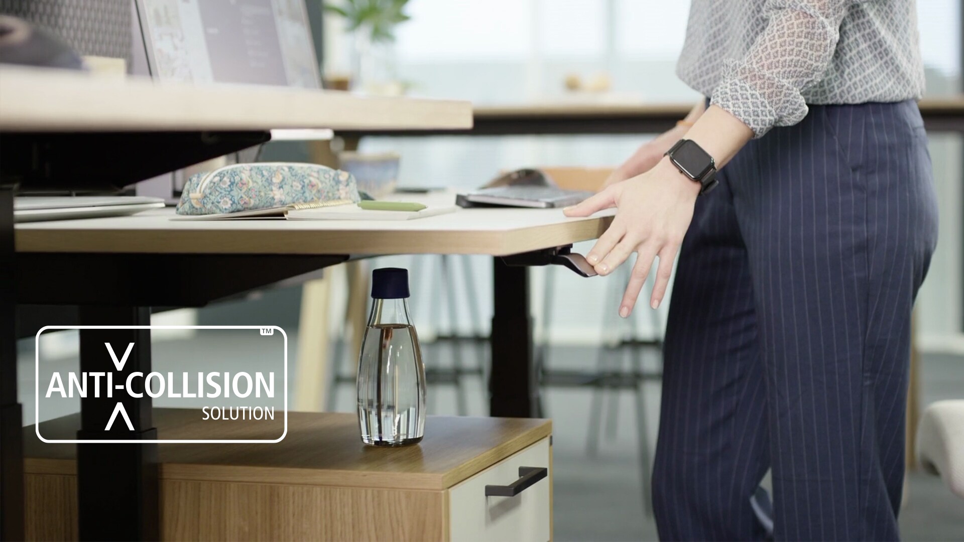 现代办公室配有符合人体工学的升降办公桌，该升降桌采用装在桌面下方设在 DPI 桌面板中的防撞技术。防撞解决方案图标。