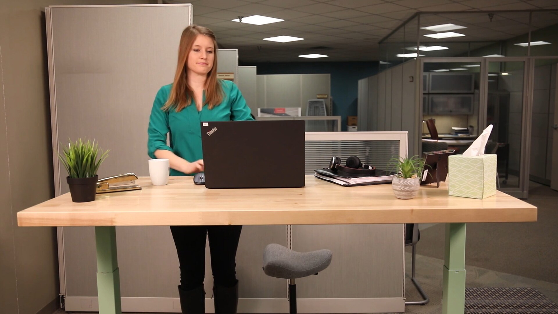 一位女士在使用装有 LINAK 产品的电动升降书桌。