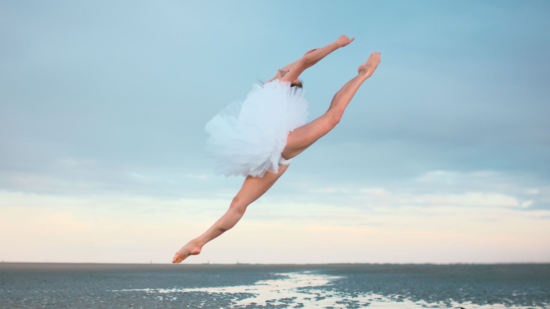 芭蕾舞演员在沙滩上跳跃，展示 LINAK 直线推杆 LA42 的灵活性